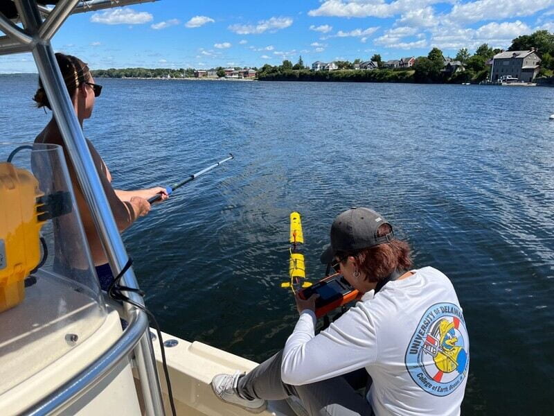 Master’s student Grant Otto (left) helps orient the AUV away from the boat while master’s student Sun Woo Park initiates the mission go command from the remote control. The Iver3 AUV is setting off to map lakebed anomalies off the War of 1812 battlefield site. Photo courtesy of Art Trembanis.